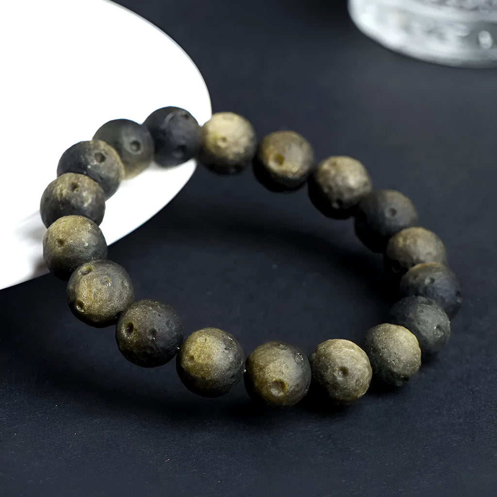 Natural obsidian crater ball bracelet with polished beads in silver or gold meteorite finish.