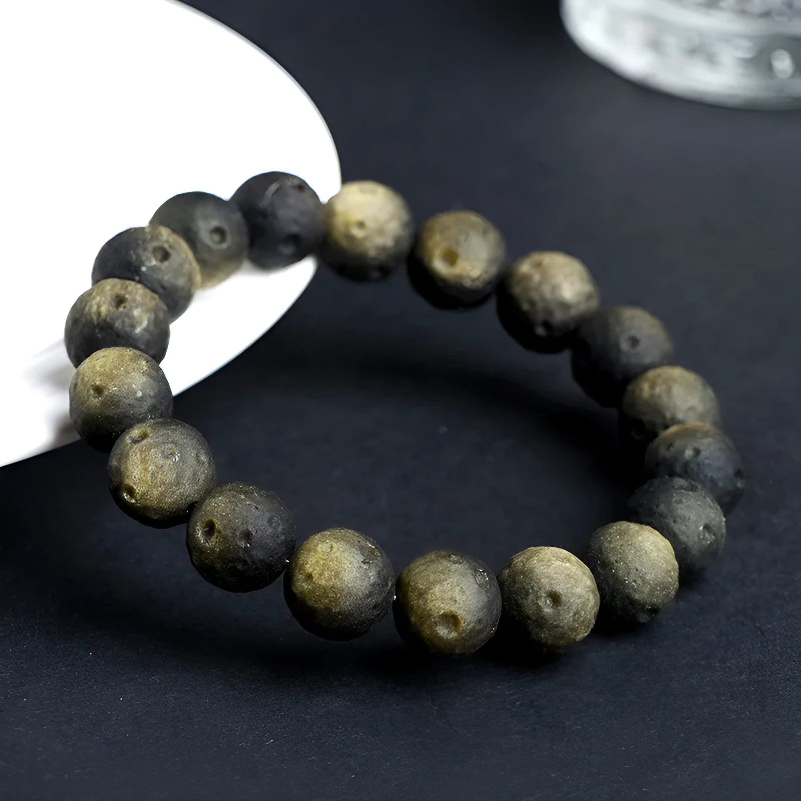 Natural obsidian crater ball bracelet with polished beads in silver or gold meteorite finish.