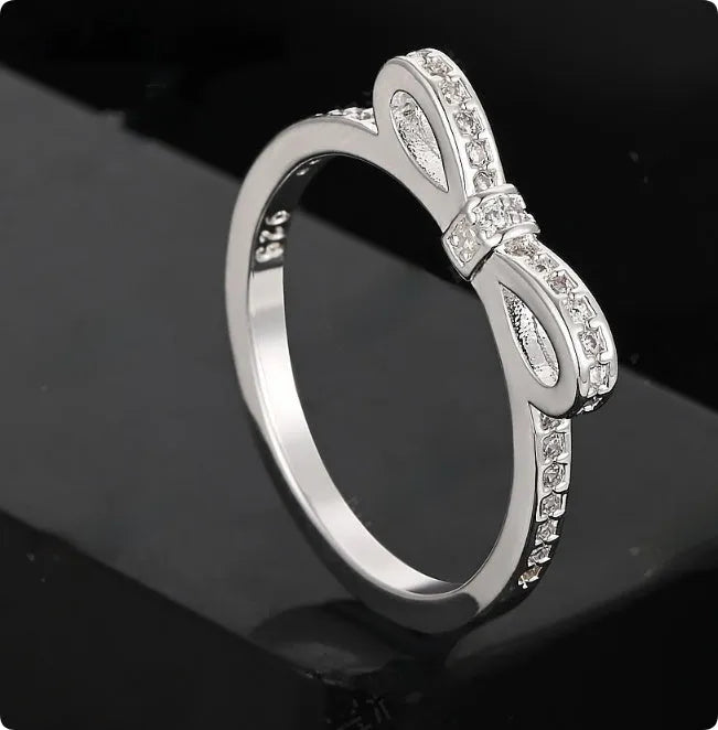 Silver bow-shaped rhinestone ring with zircon crystals on finger
