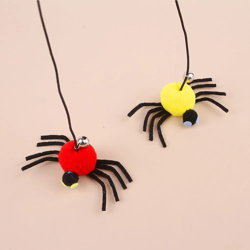 Red door hanging cat toy with elastic rope, feather, bell, and spider attachment on a white door.