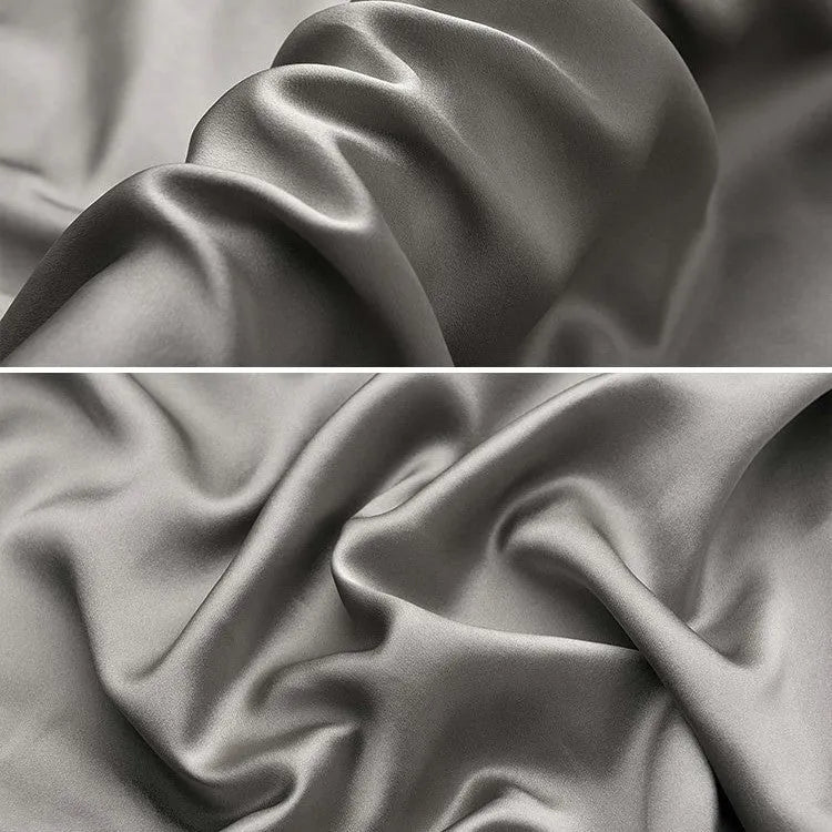 Dark grey mulberry silk pillowcase with an envelope closure on a bed.
