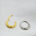 Close-up of a titanium alloy concave-convex nose ring in gold finish, showing carved detail and ring shape.