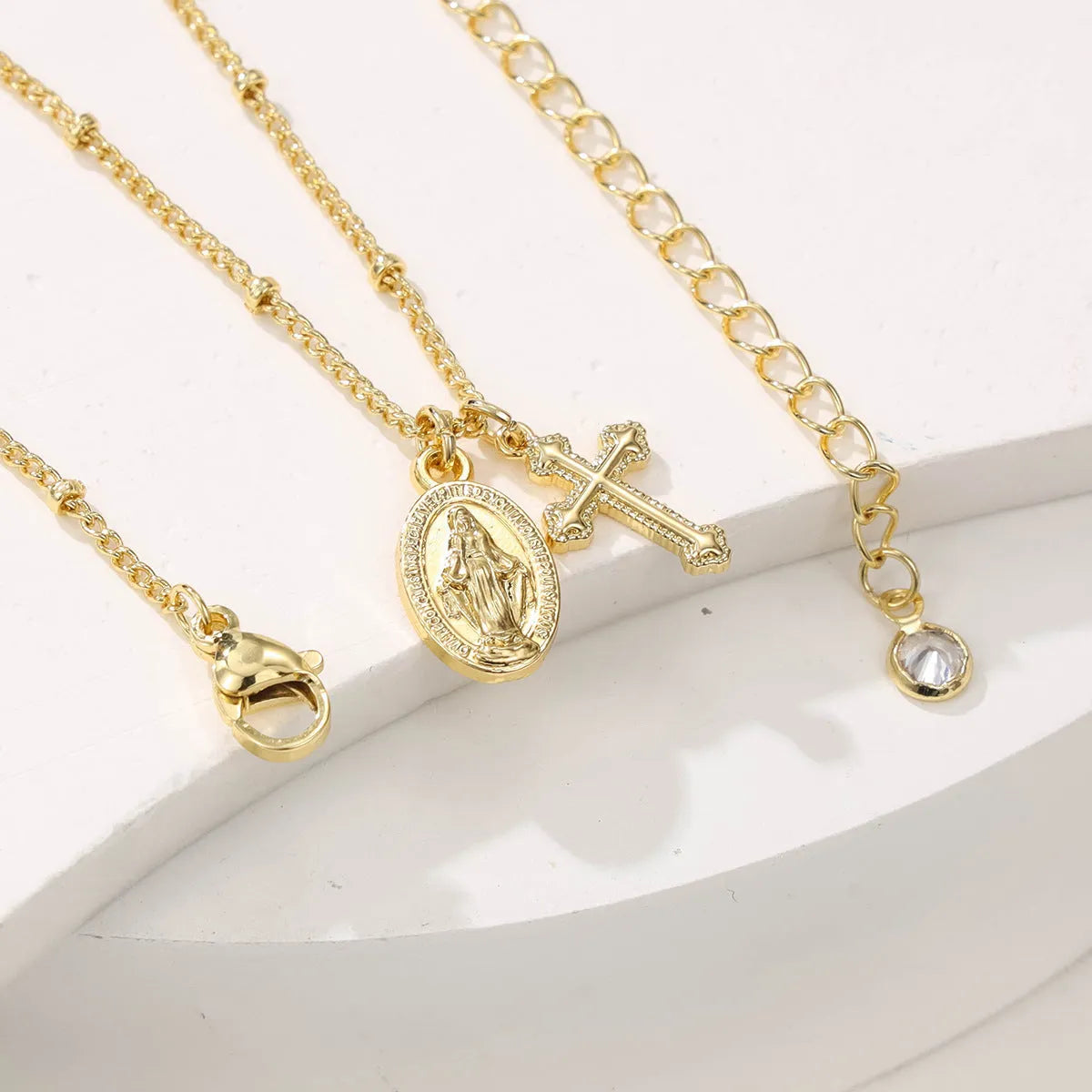 Geometric shaped gold tone pendant necklace with Cross and Virgin Mary ornament.