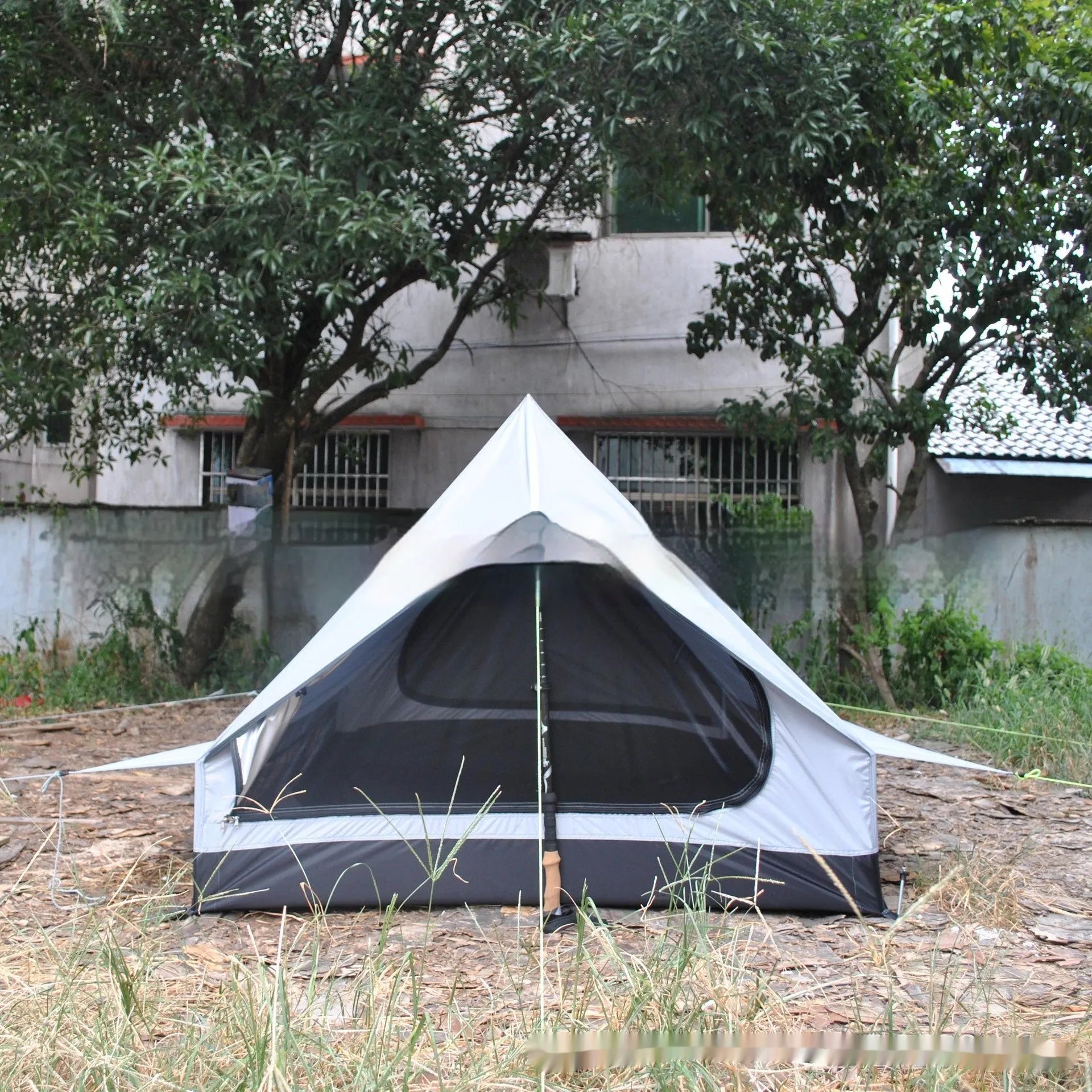 Brown or white A-line cabin tent pitched with trekking poles, showing spacious interior and waterproof fabric construction