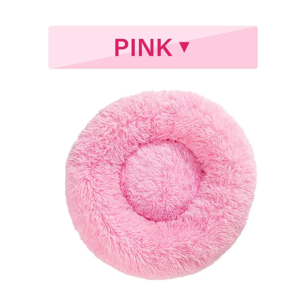 Fluffy donut-shaped dog bed in long plush material, shown in a light grey colour with a raised edge.
