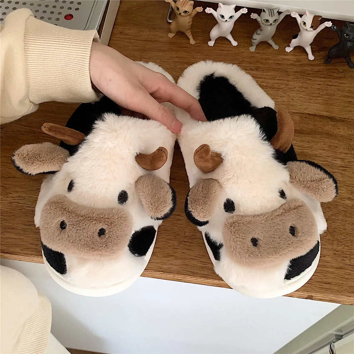 White plush cow slippers for women with a non-slip textured sole.
