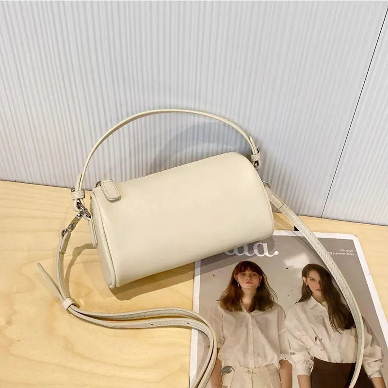 Vegetable-tanned leather crossbody phone bag with cylindrical shape and visible sewing thread detailing