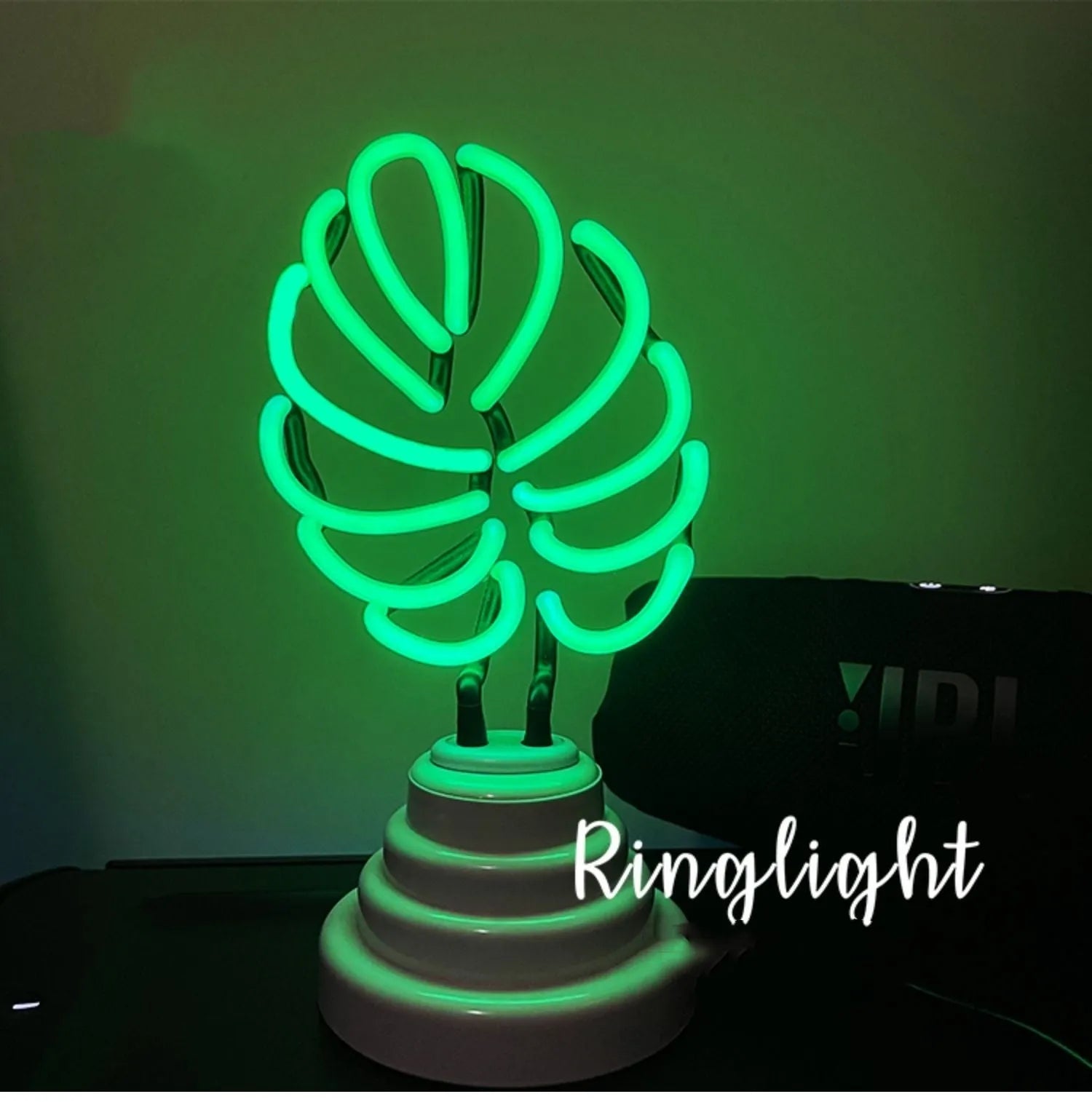 White bamboo-shaped desktop lamp with green light tube on a wooden desk.