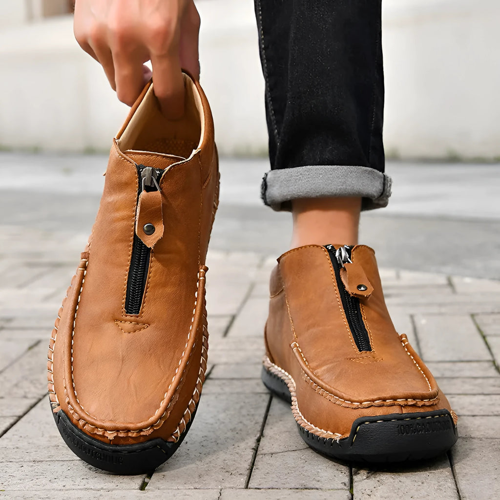 Men's black slip-on leather loafers with round toe and stitching detail on a solid colour background.