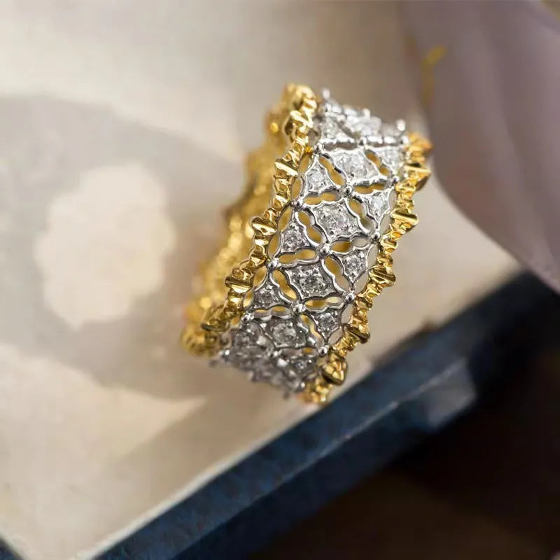 Gold two-tone copper ring with round geometric zircon centrepiece on a plain background.