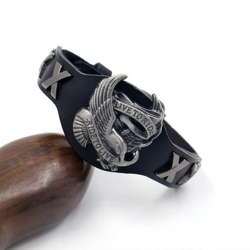 Black geometric leather bracelet with a detailed eagle watch-button clasp, shown flat.