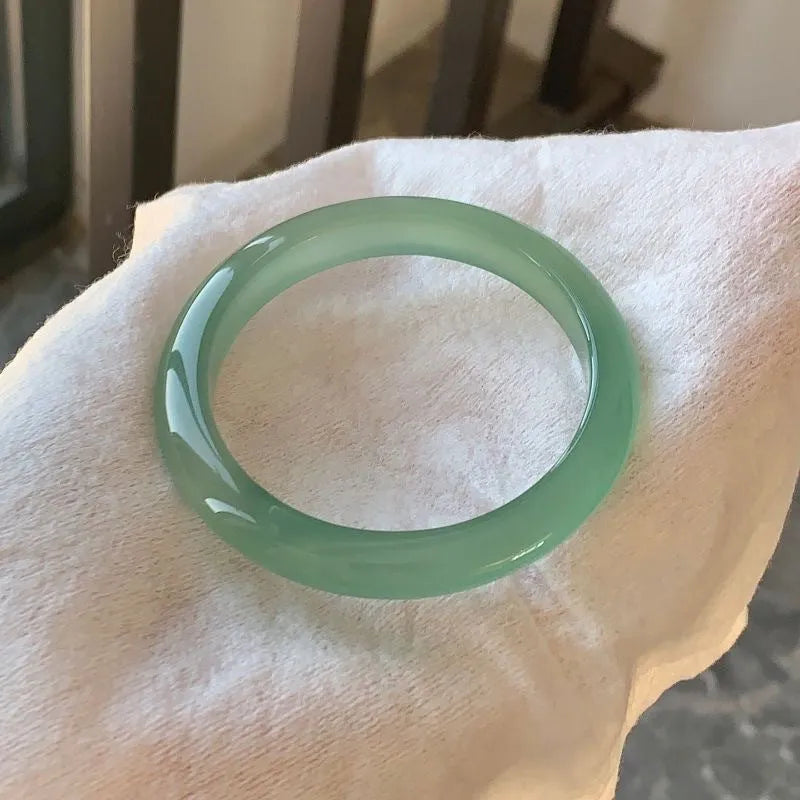 Natural agate wide tyre bracelet with cherry blossom jade accent on wrist, showing colour options.