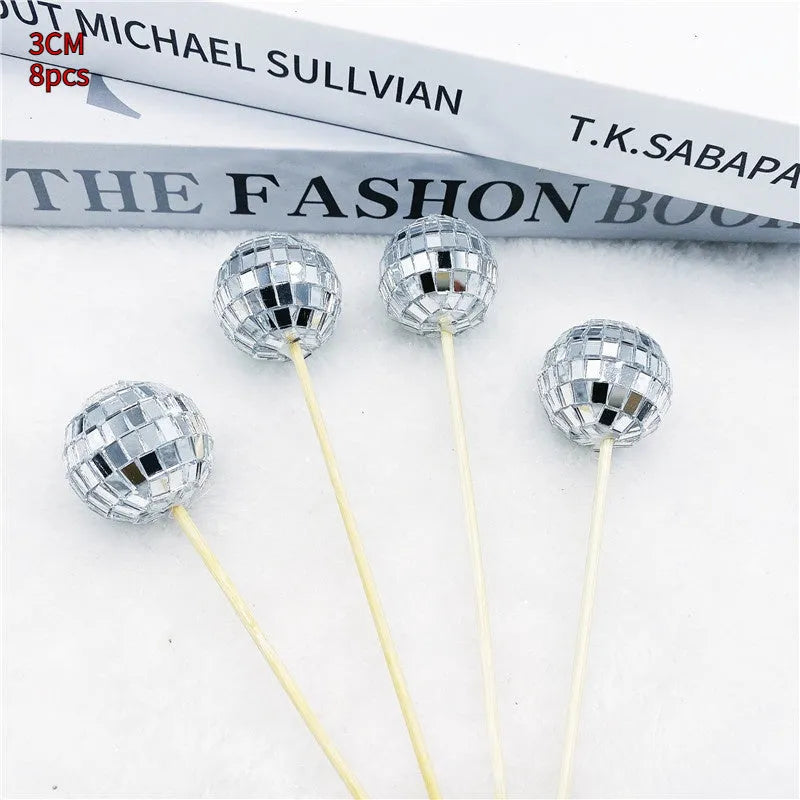 Silver reflective glass disco ball cake topper on a wooden stick for birthday party decoration.