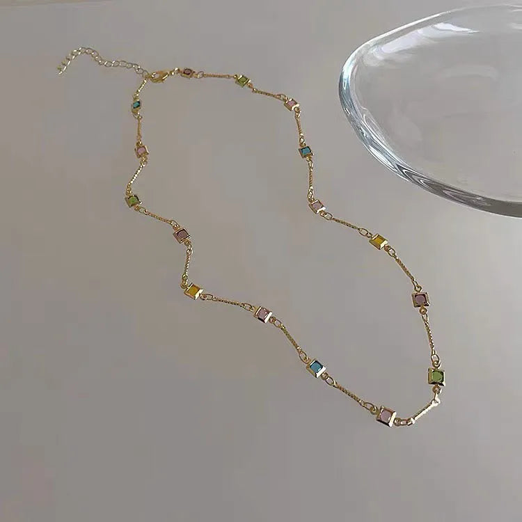 Fine gold-tone geometric necklace with a square clear crystal pendant on a clavicle-length chain.