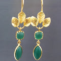 A pair of gold-colour drop-shape earrings with zircon stones and water droplet design elements on a copper base.