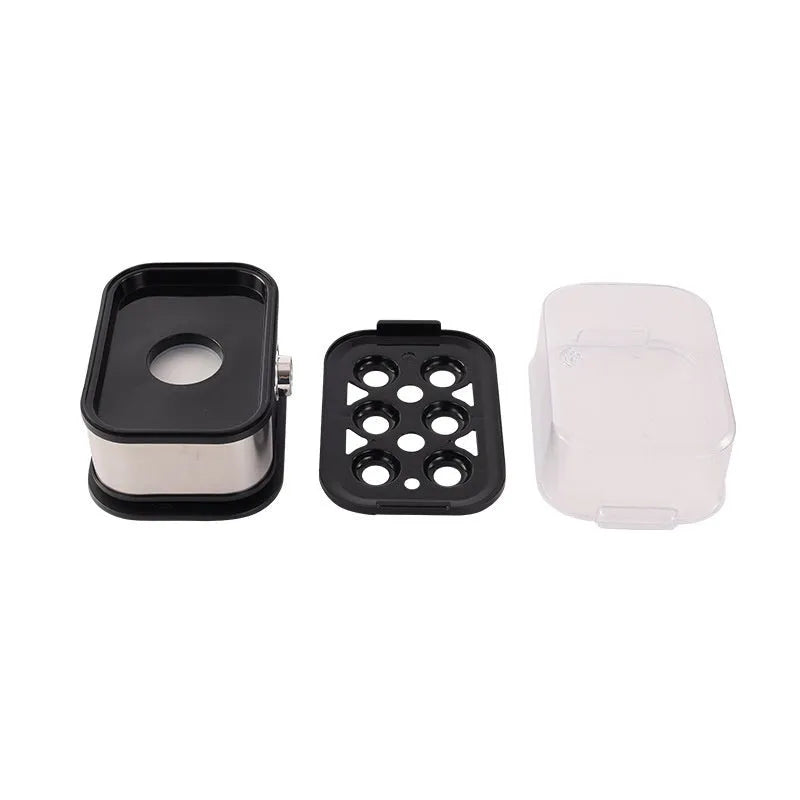 Small black stainless steel portable egg boiler with plug adapters on a countertop.