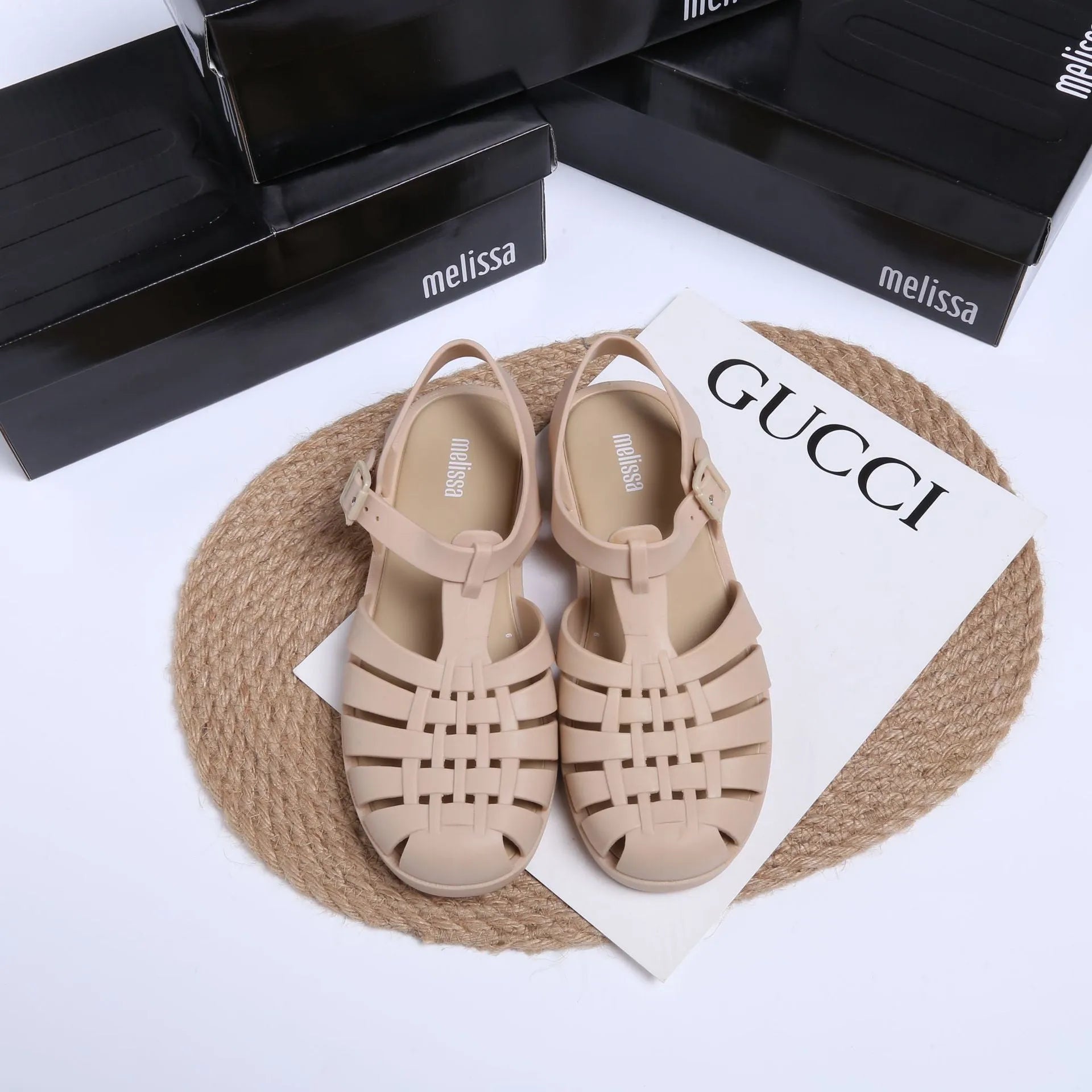 Matte black Roman style sandals with buckle fastening and PVC upper on wooden surface