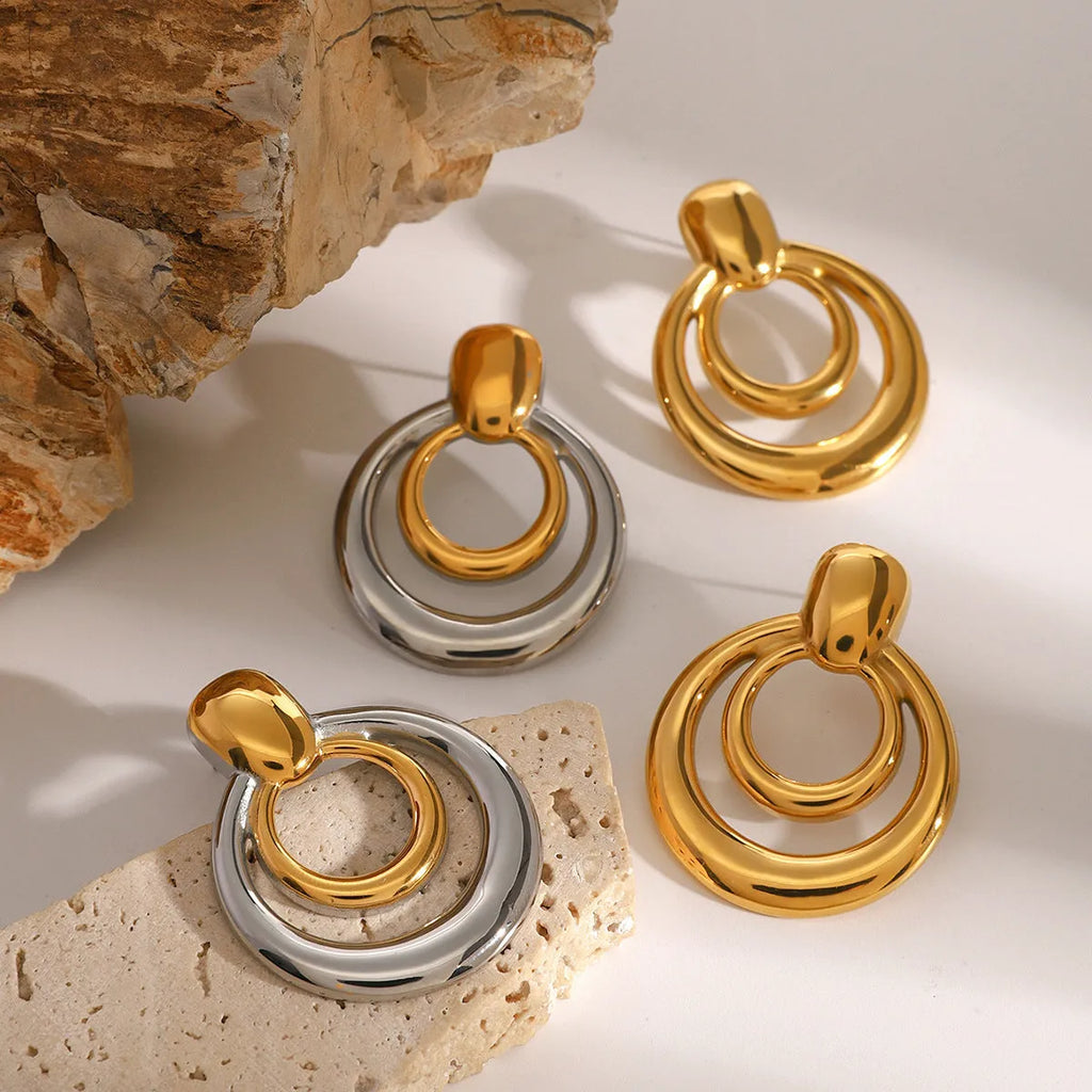 Round gold-coloured geometric hollow stud earrings on a white background.