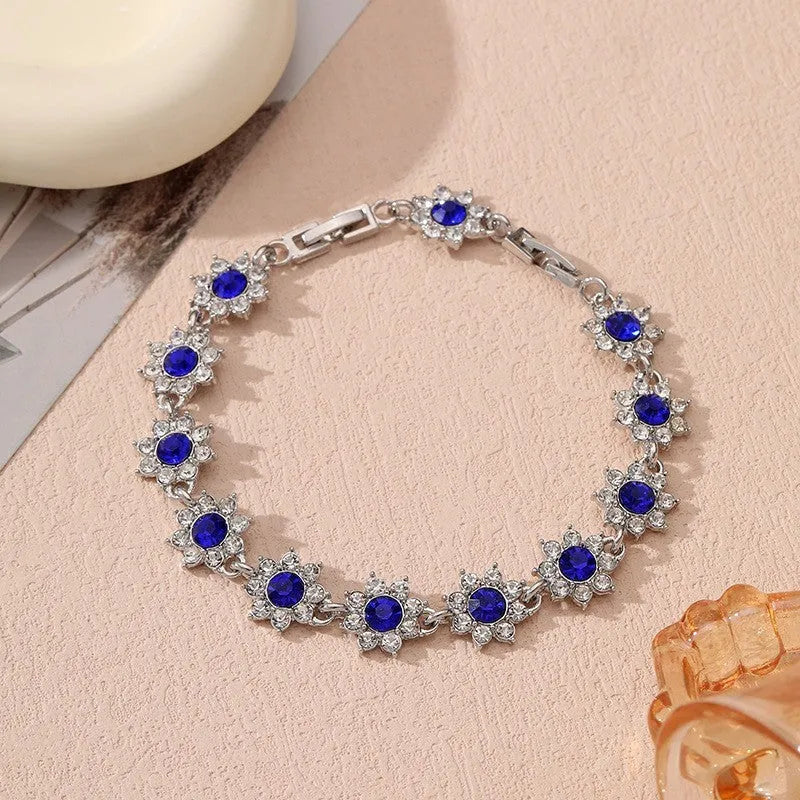 A gold or silver electroplated zinc alloy flower bracelet with coloured gems.