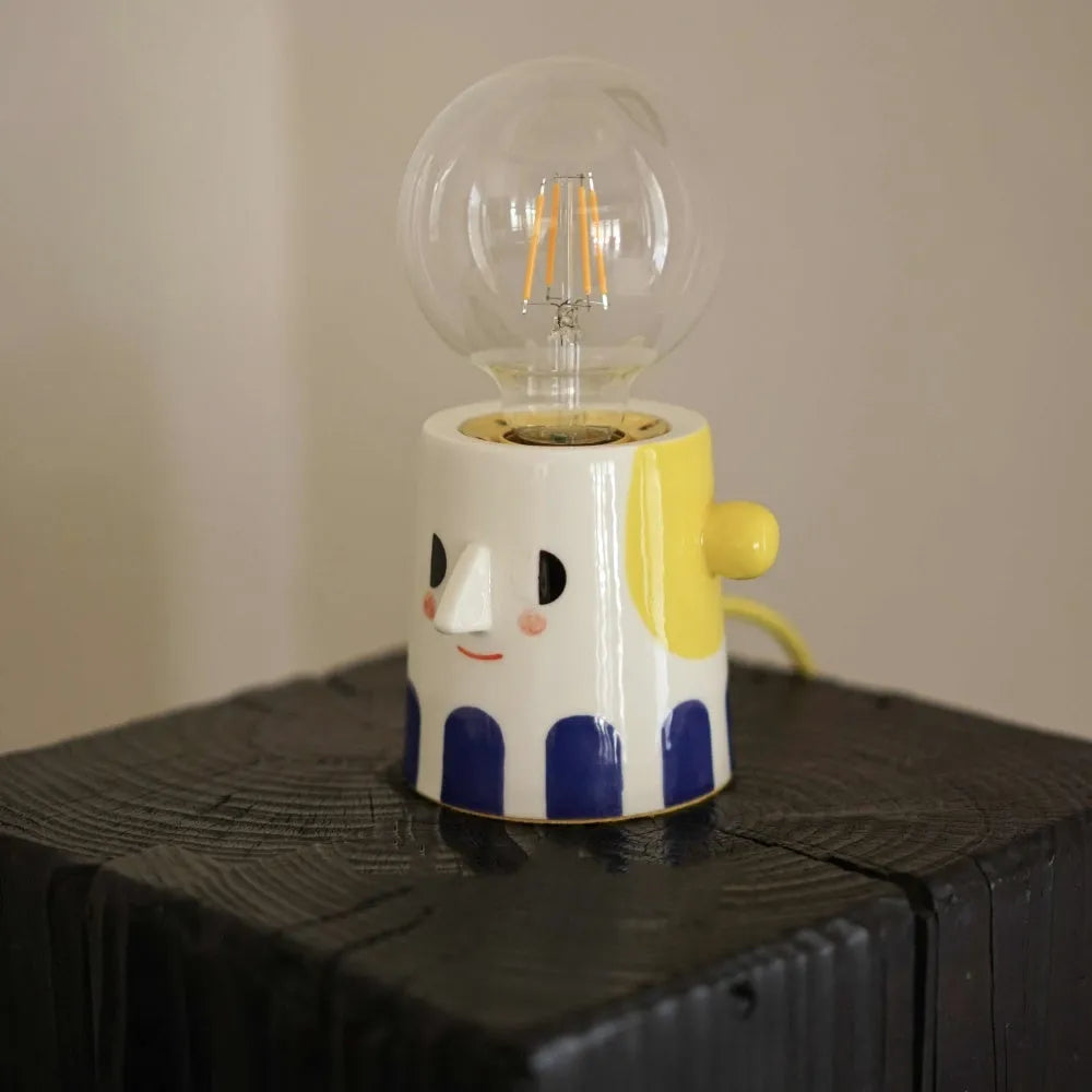 Handmade ceramic table lamp with a ball-shaped headlight on a neutral background.