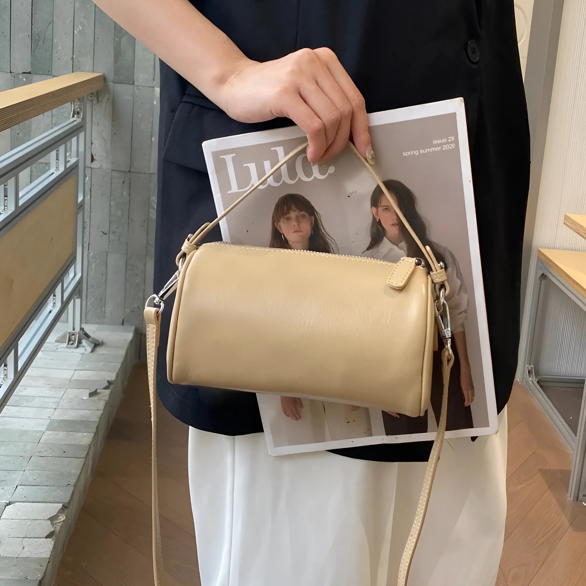 Vegetable-tanned leather crossbody phone bag with cylindrical shape and visible sewing thread detailing