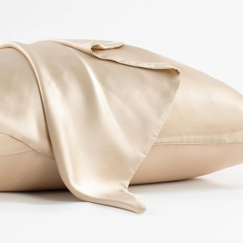 Dark grey mulberry silk pillowcase with an envelope closure on a bed.