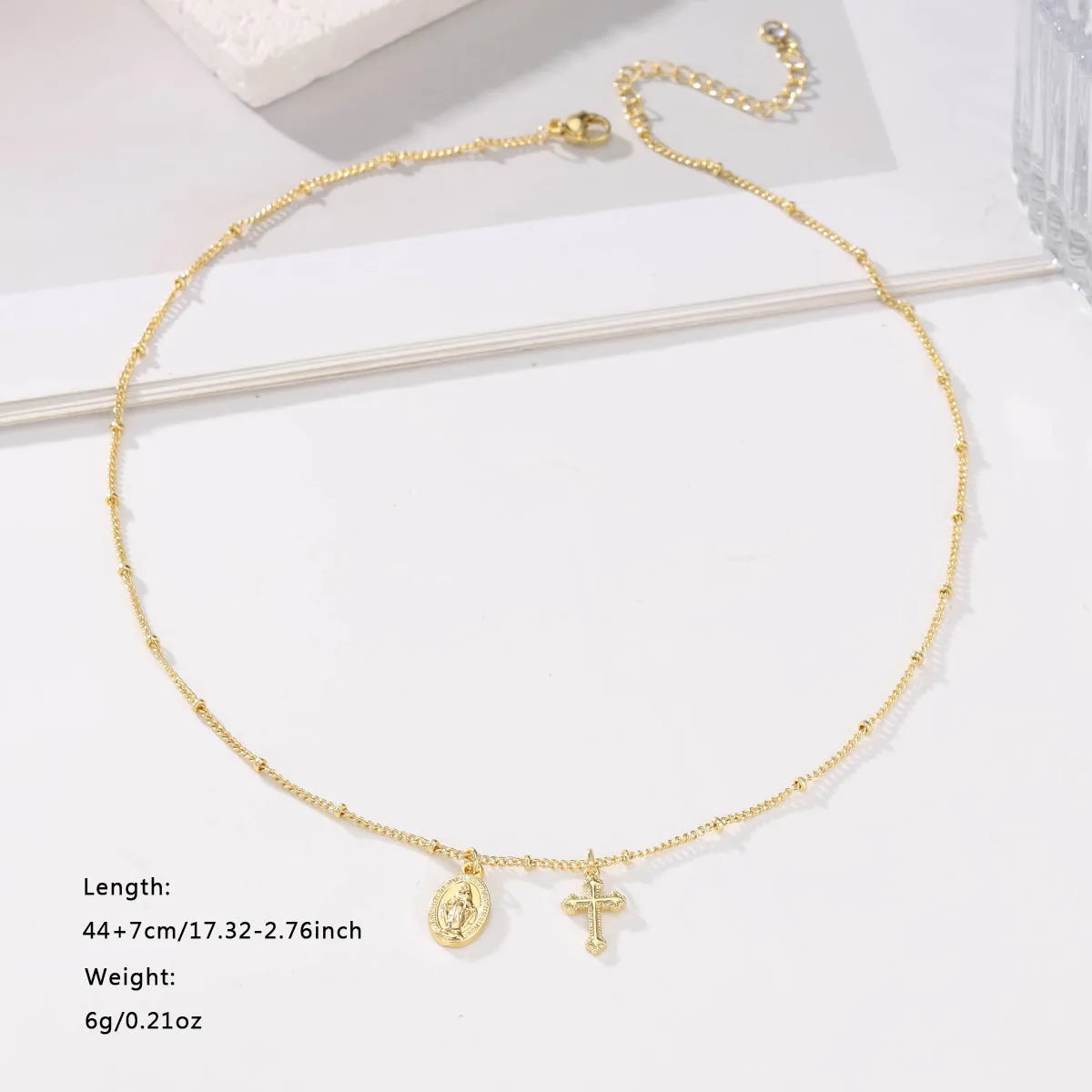 Geometric shaped gold tone pendant necklace with Cross and Virgin Mary ornament.