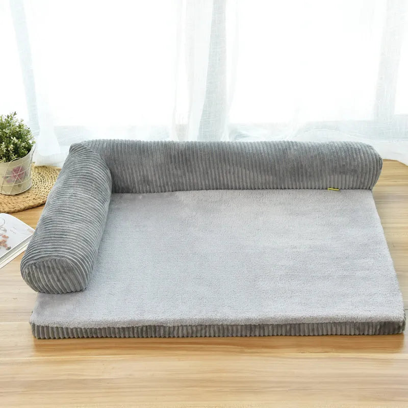 A corduroy pet sofa dog bed with a raised bolster, shown in a grey colour on a wooden floor.