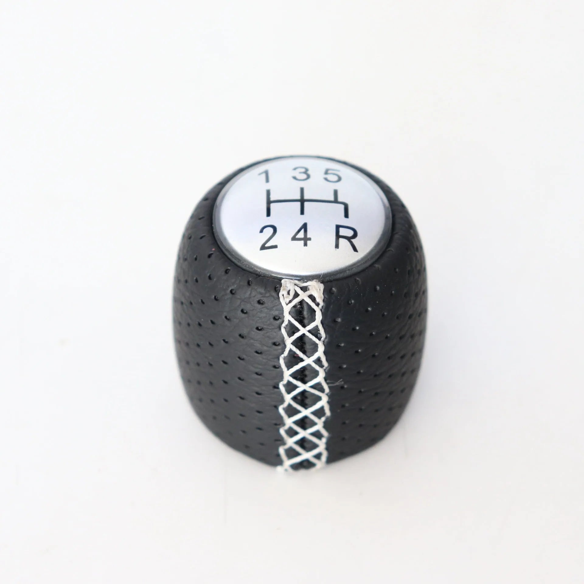 Sewn wrapped black perforated leather gear shift handball for Alpha vehicles on a silver cover.