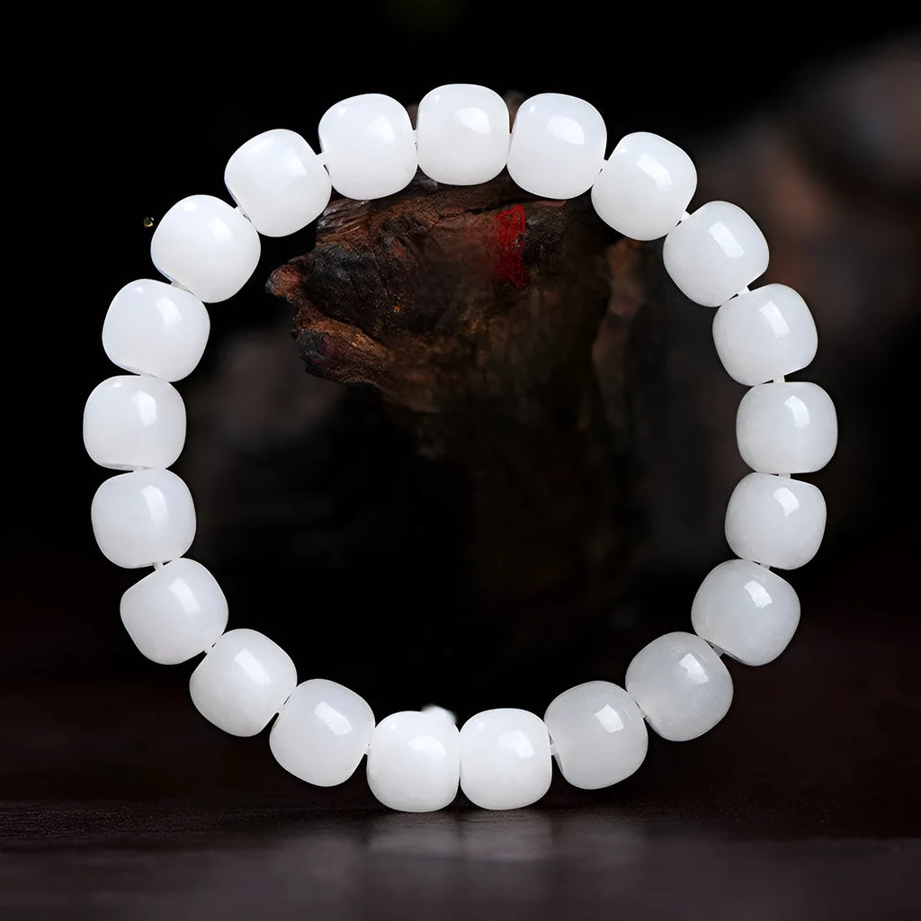White Hetian jade barrel bead bracelet on a wrist, showing traditional unisex design.