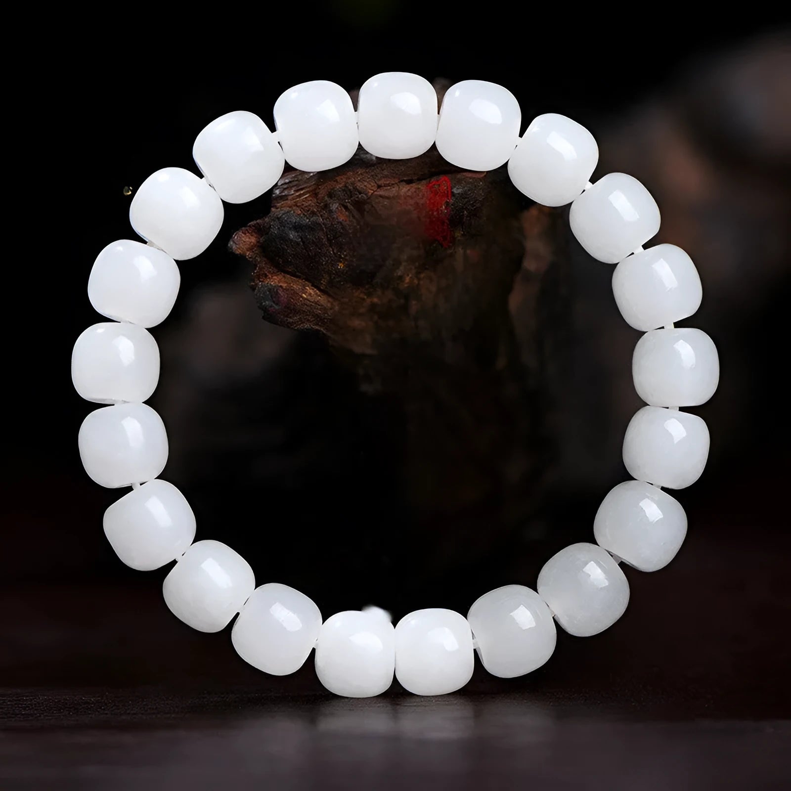 White Hetian jade barrel bead bracelet on a wrist, showing traditional unisex design.