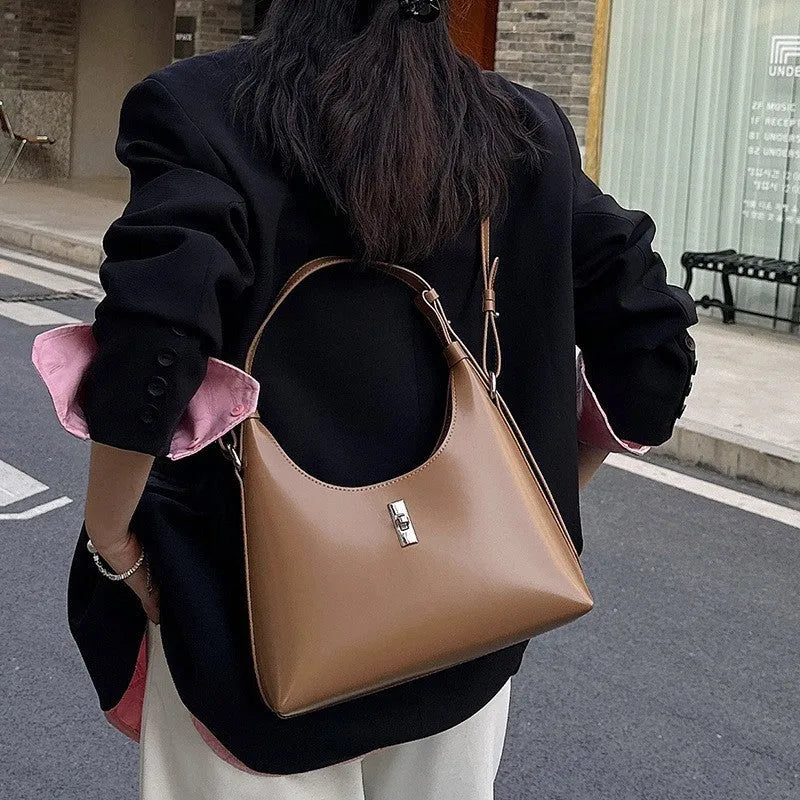 A soft genuine leather dumpling-shaped crossbody shoulder bag in a street style, shown with internal phone pocket.
