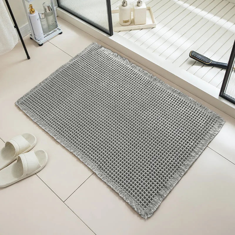 Square checkered-pattern non-slip bathroom carpet in a neutral colour on tiled floor.