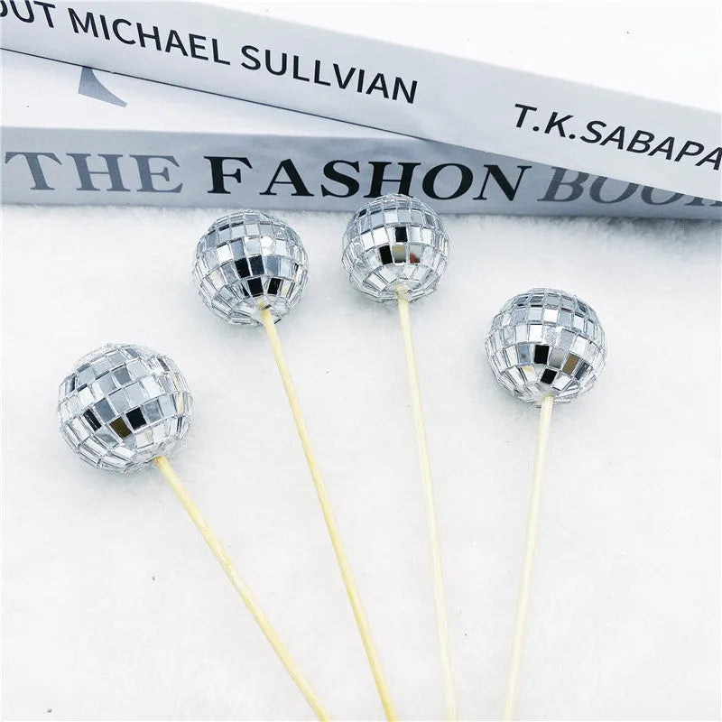 Silver reflective glass disco ball cake topper on a wooden stick for birthday party decoration.