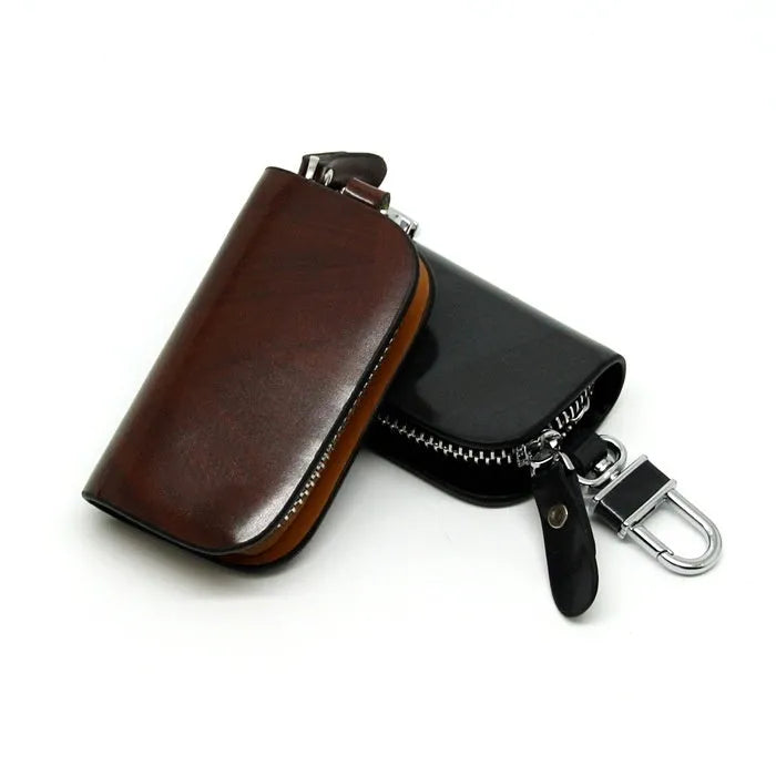 Black frosted leather car key case with zipper, next to a car key