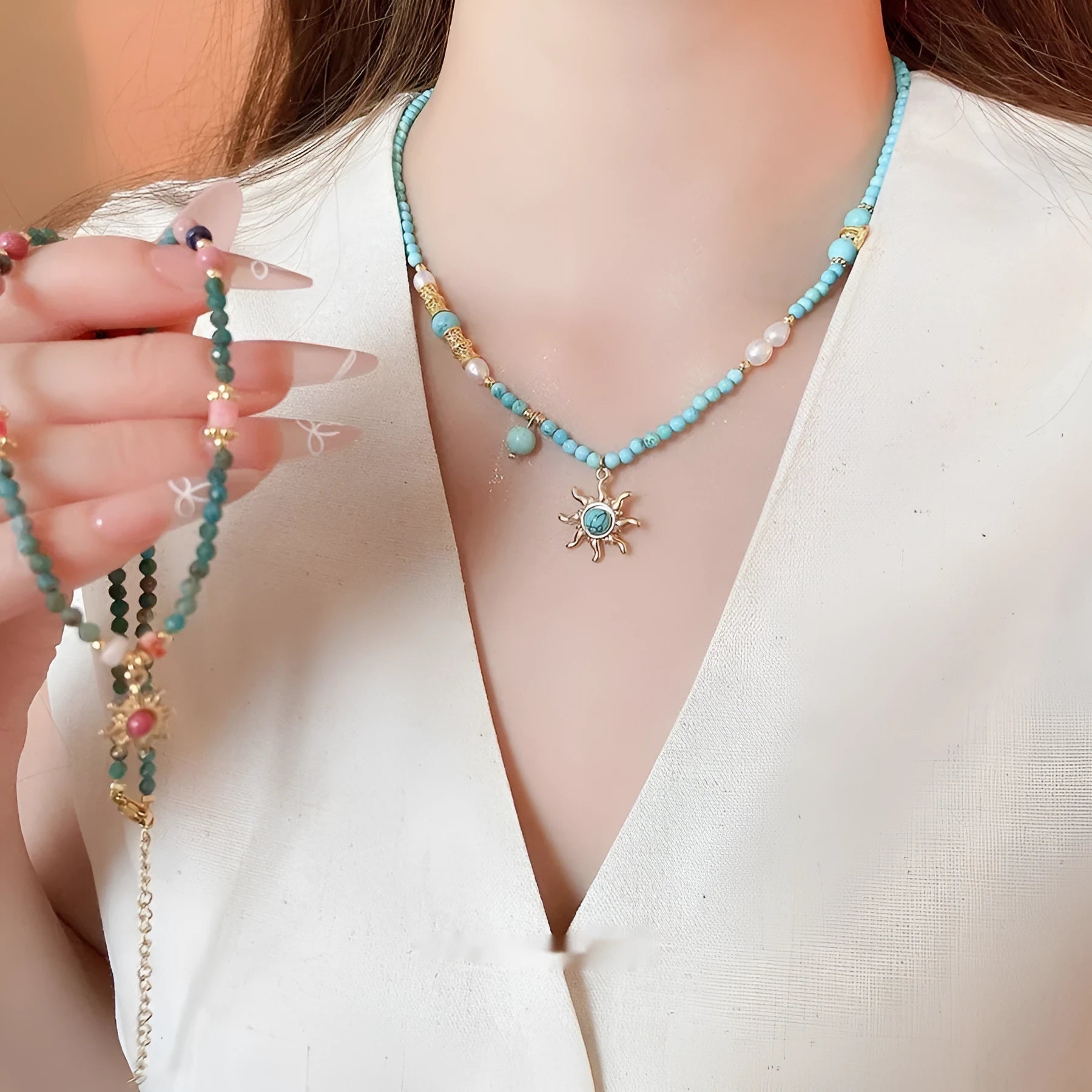Close-up of a freshwater pearl and geometric stone sun necklace on an adjustable clavicle chain.