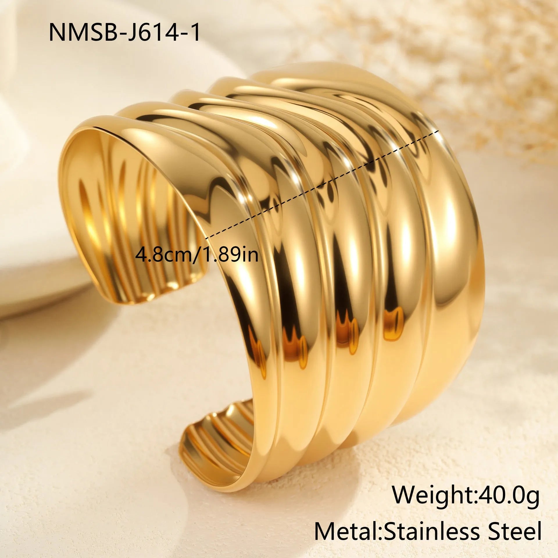 Women's wide stainless steel bracelet with 18K gold plating showing geometric wave patterns