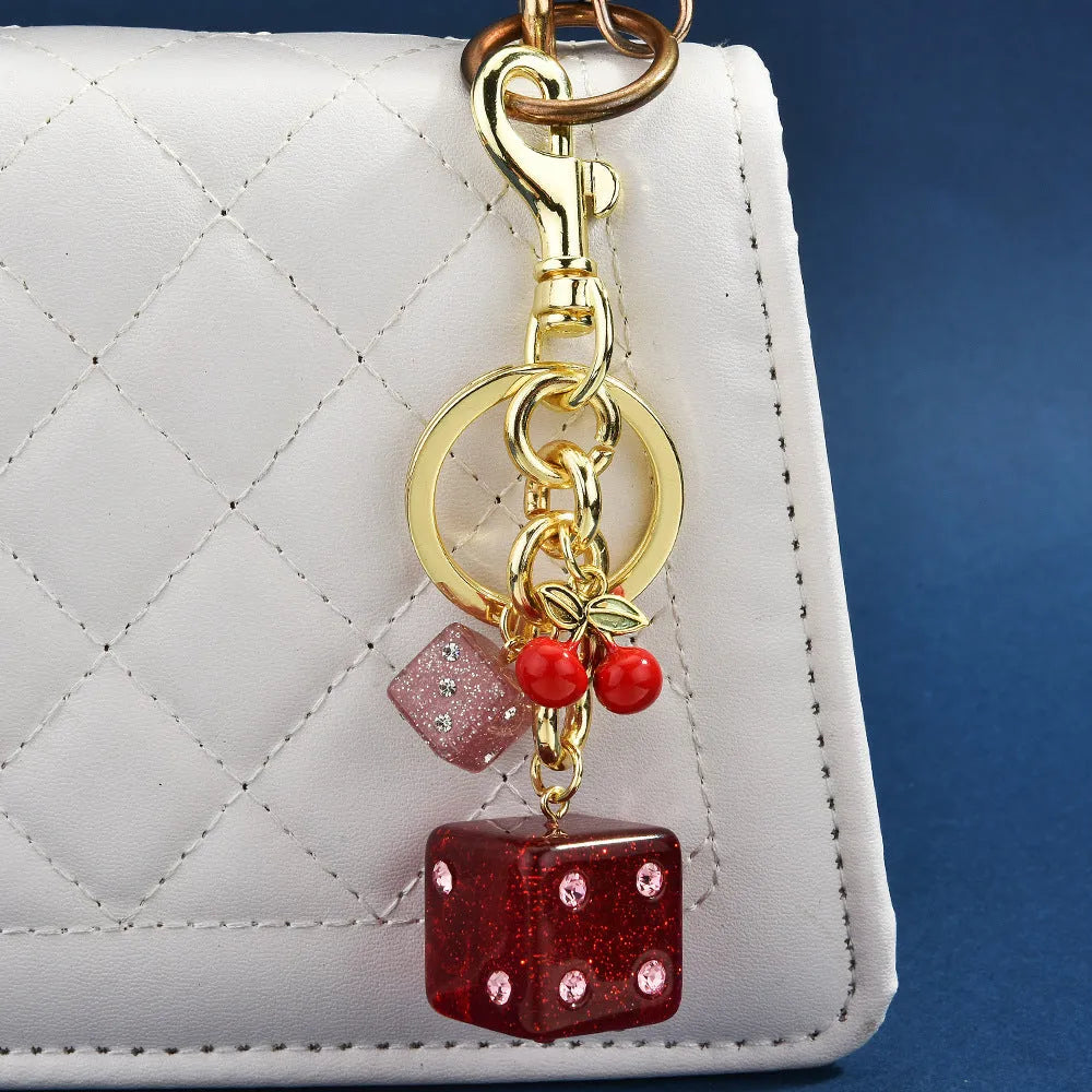 Vintage cherry red two-tone dice pendant on a metal keychain, a retro suitcase ornament.