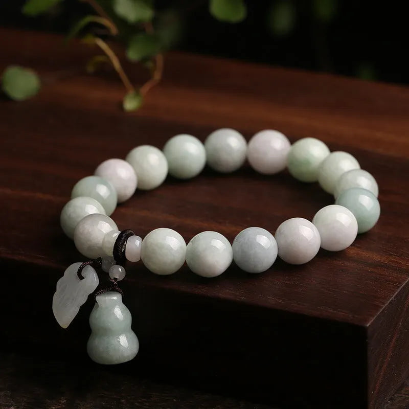 Natural green jade bracelet with a geometric pendant charm on a wrist.