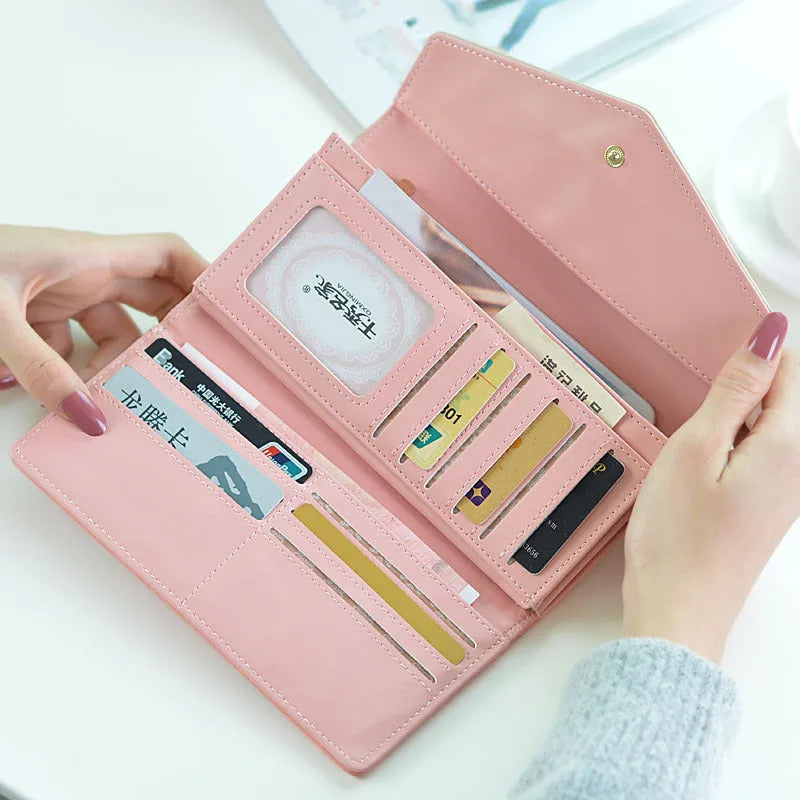 Women's black trifold leather wallet with buckle clip closure showing card slots and coin compartment