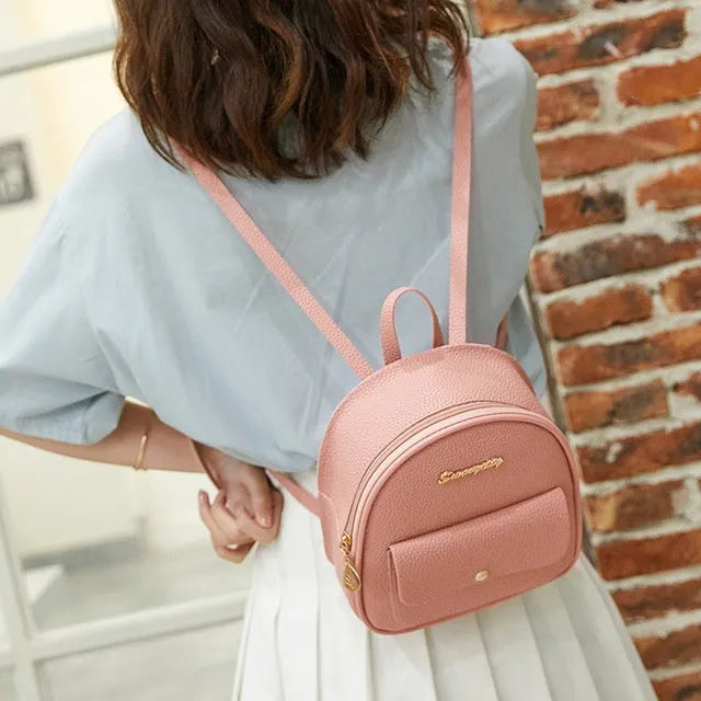 Small black PU shoulder backpack for women with zipper, shown next to a mobile phone for scale.