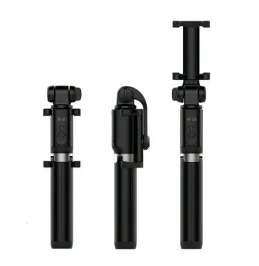 Black Bluetooth selfie stick with extended tripod legs and remote control next to a mobile phone.