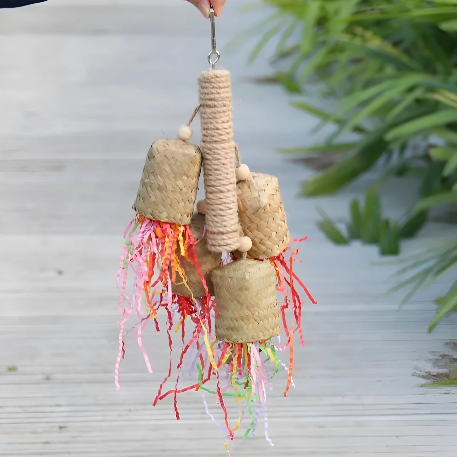 Wooden parrot chew toy with colourful shredded paper hanging from sisal rope