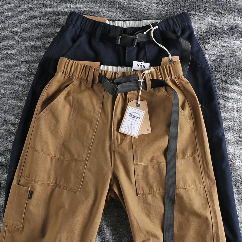 Men's khaki cotton work trousers with N buckle belt on a mid waist, showing three-dimensional cut.