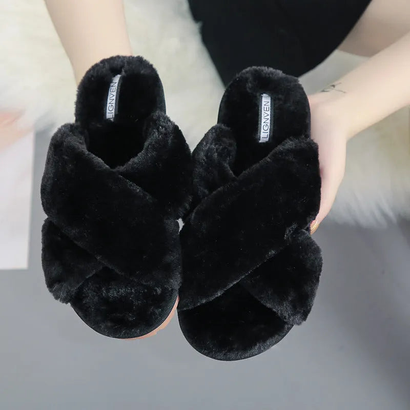 Women's black cross open-toe fur slippers with a patterned non-slip sole on a wooden floor