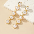 White metal drop tassel earrings with pearl water flow design on display