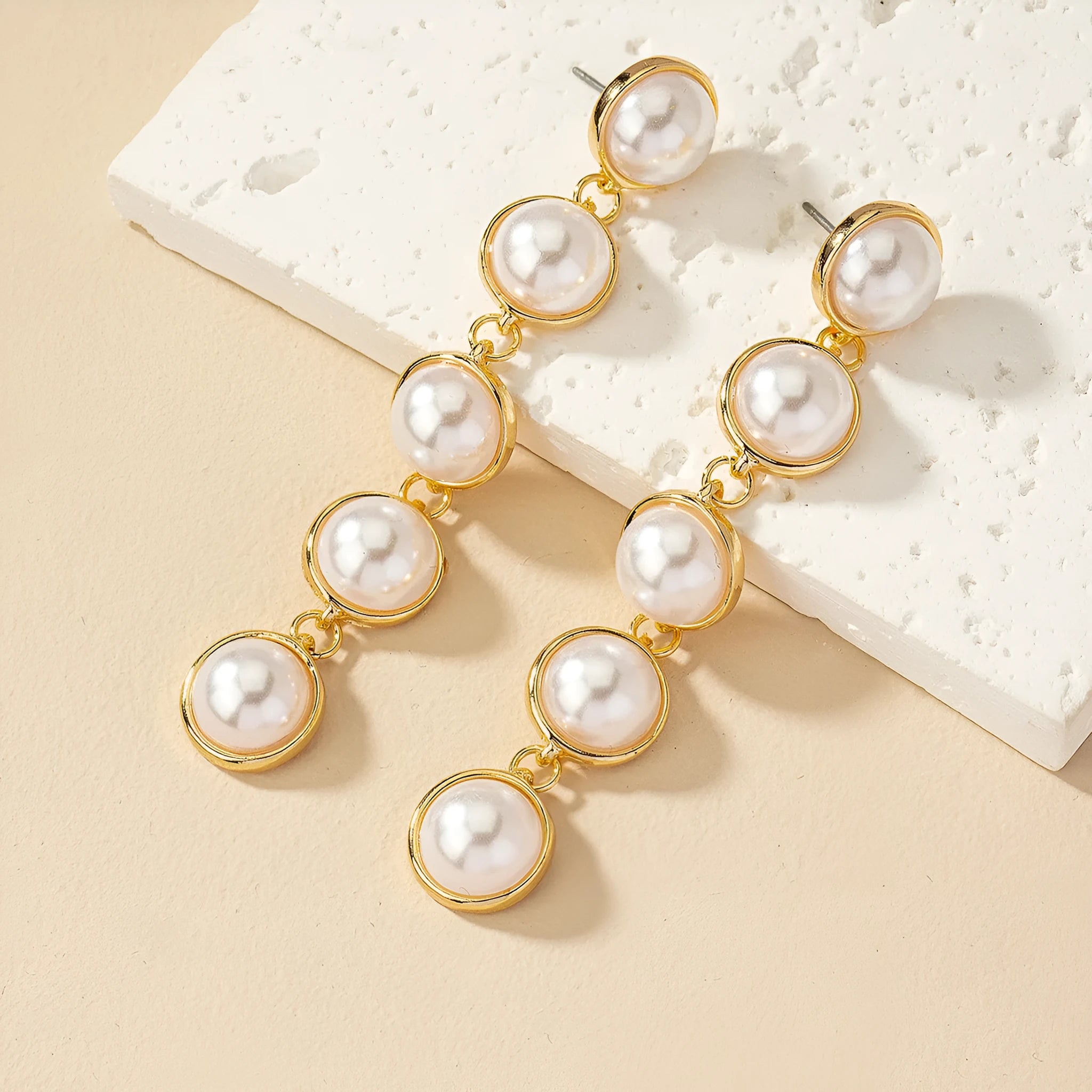 White metal drop tassel earrings with pearl water flow design on display