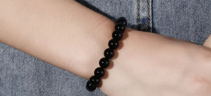 Women's geometric black agate bracelet with 8mm beads on a black elastic cord.