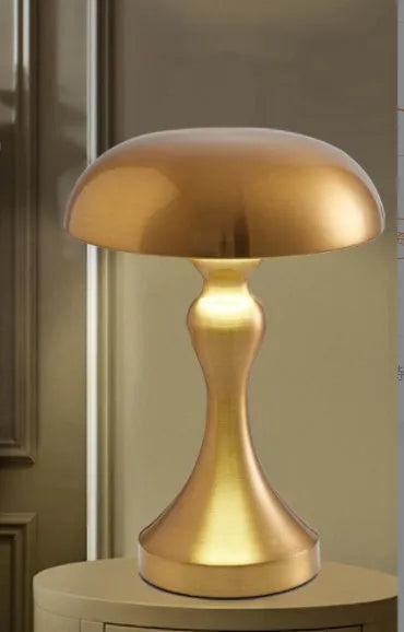 Metallic USB-rechargeable LED desk lamp with touch control for three light colours on a wooden desk.