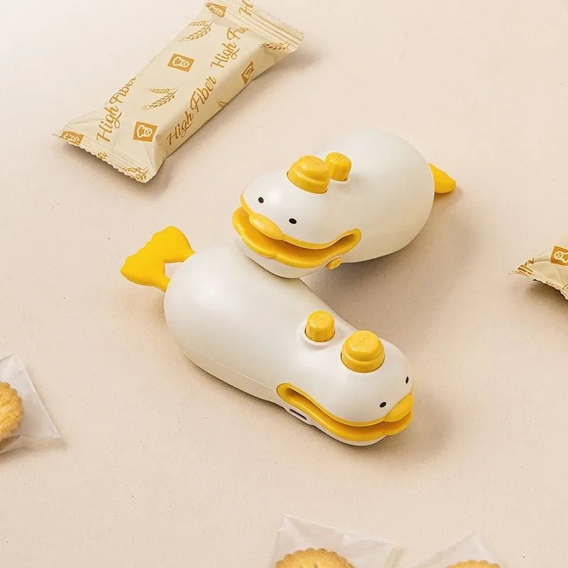 Small yellow duck shaped rechargeable sealing machine with charging cable on a white background.
